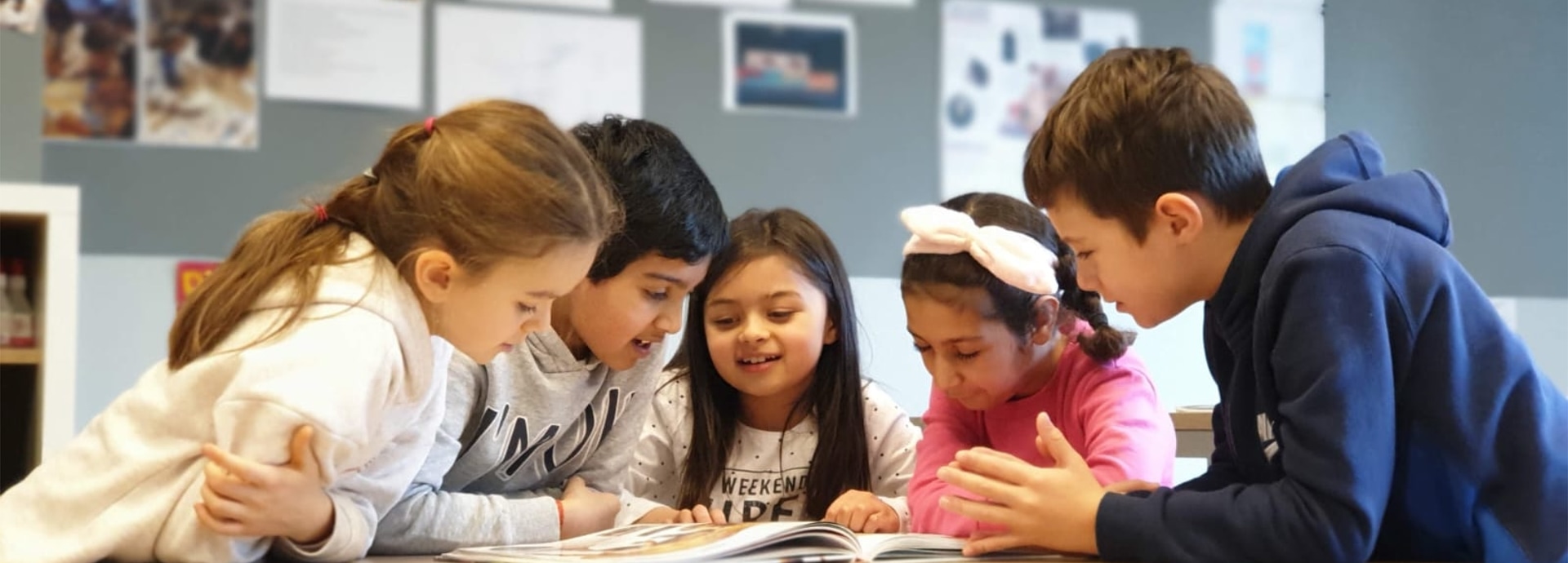 international children reading a book together